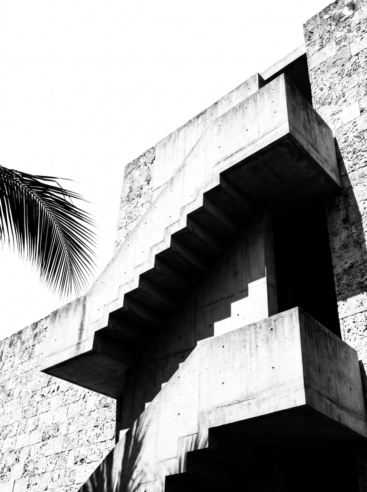 Cantilevered concrete stair against a coral stone wall